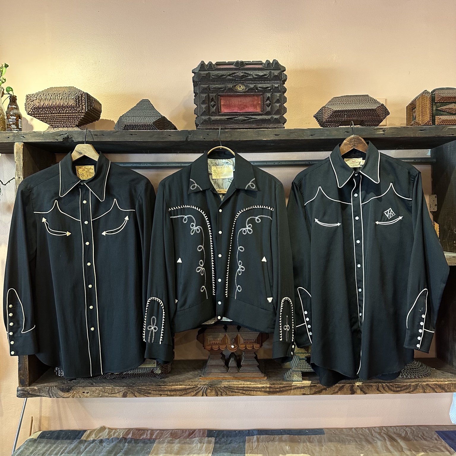Two pairs of metallic vintage cowboy boots displayed on a wooden crate.
